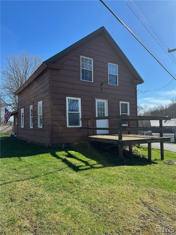 back of house featuring a deck and a lawn