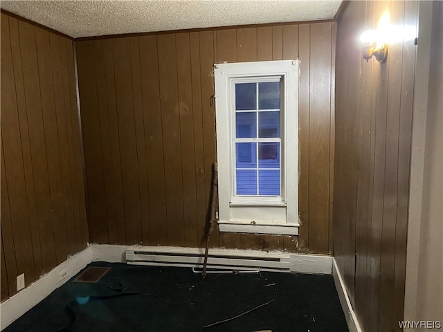 room details featuring a baseboard radiator, wood walls, and a textured ceiling