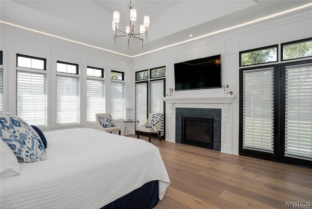 bedroom with an inviting chandelier, hardwood / wood-style flooring, and a high ceiling