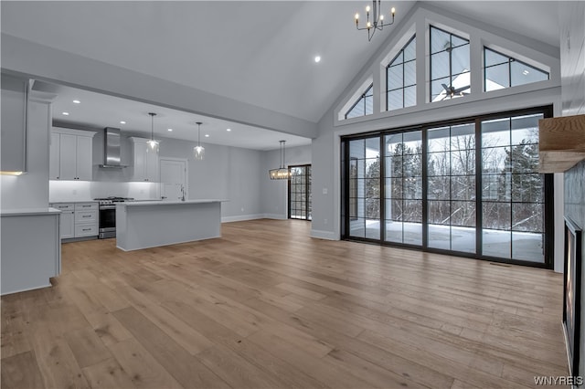 unfurnished living room with a notable chandelier, light hardwood / wood-style flooring, and high vaulted ceiling