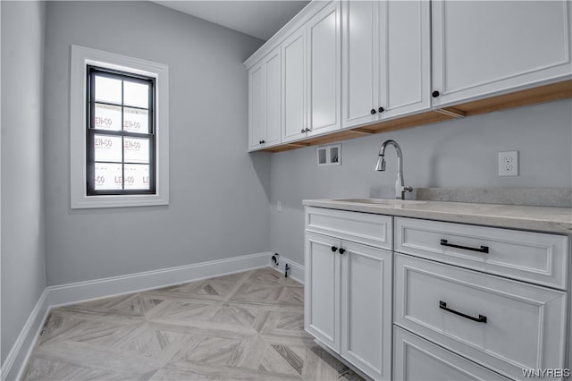 clothes washing area with light parquet flooring, washer hookup, cabinets, and sink