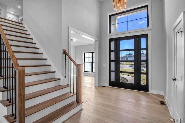 foyer featuring a towering ceiling, a chandelier, and light hardwood / wood-style flooring