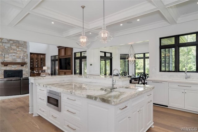 kitchen featuring white cabinets, a fireplace, light hardwood / wood-style flooring, and sink