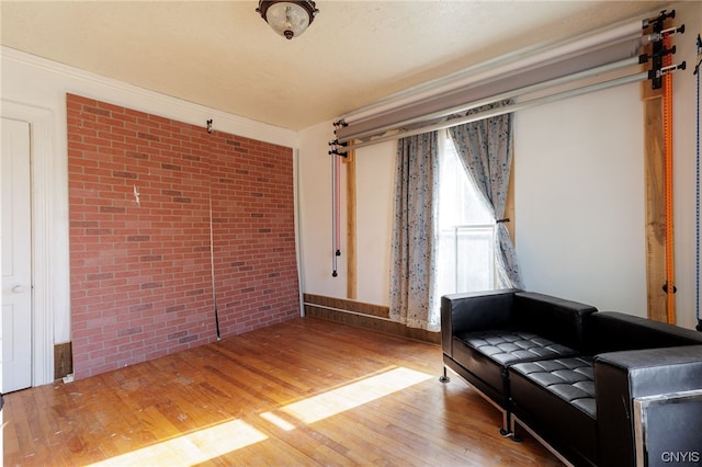 sitting room featuring brick wall and hardwood / wood-style floors