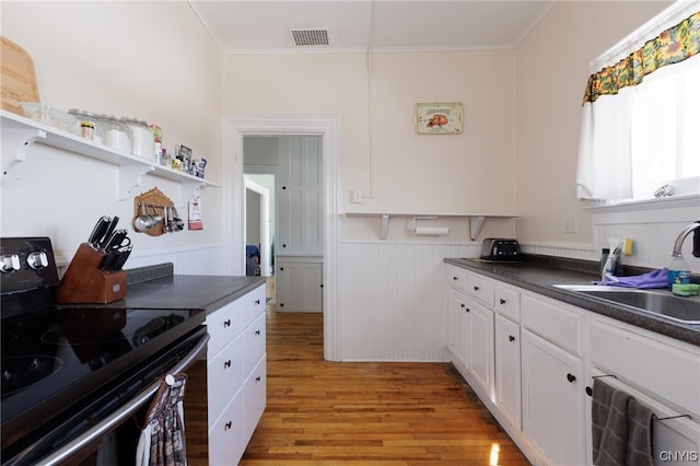 kitchen featuring light wood-type flooring, white cabinets, electric range, and ornamental molding