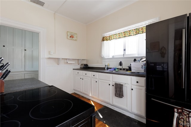 kitchen featuring light wood-type flooring, black appliances, sink, and white cabinets