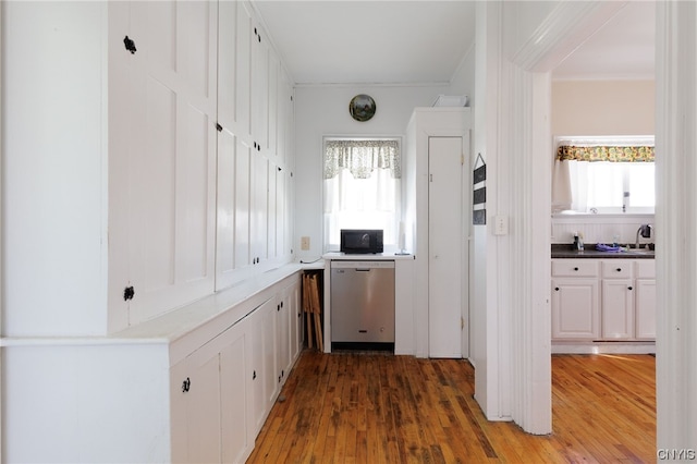 kitchen featuring hardwood / wood-style floors, dishwasher, ornamental molding, and white cabinets