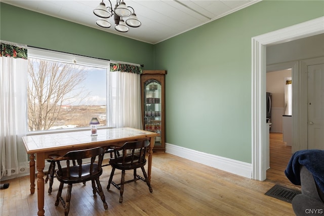 dining space with light hardwood / wood-style flooring and a chandelier