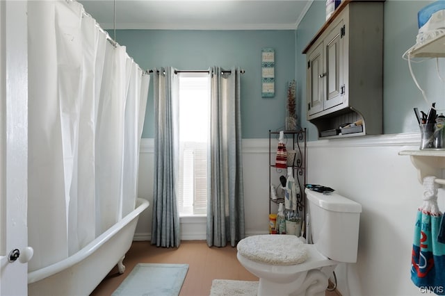 bathroom featuring a wealth of natural light, a tub, toilet, and ornamental molding