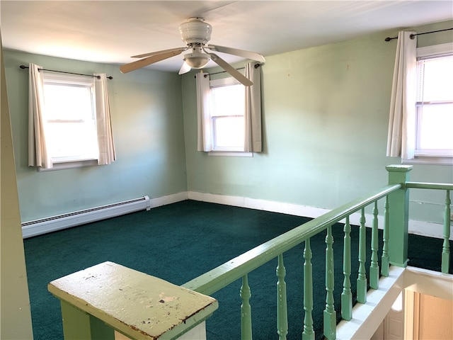 unfurnished room with ceiling fan, a baseboard heating unit, carpet floors, and plenty of natural light