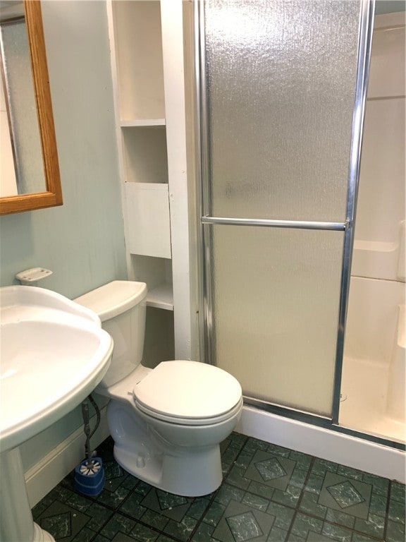 bathroom featuring a shower with shower door, toilet, and tile patterned flooring