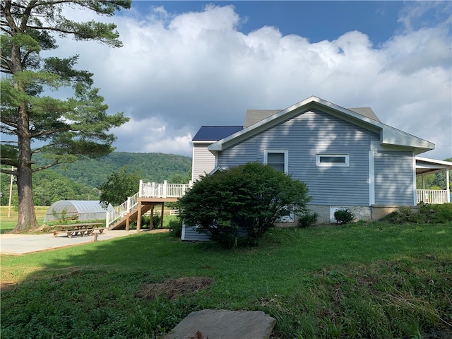 view of property exterior featuring a wooden deck and a lawn