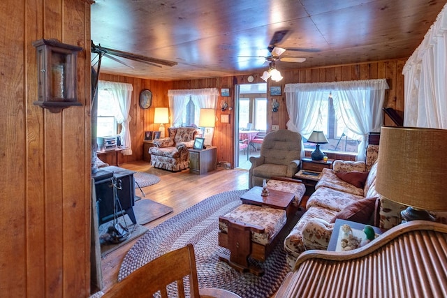 living room with hardwood / wood-style floors, ceiling fan, and wood walls