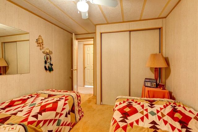 carpeted bedroom with ceiling fan, a textured ceiling, and a closet