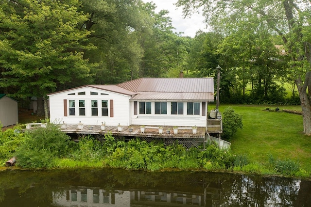 rear view of property featuring a deck with water view and a yard