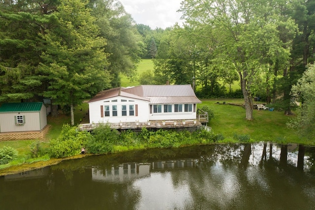 back of property with an outbuilding, a yard, and a water view