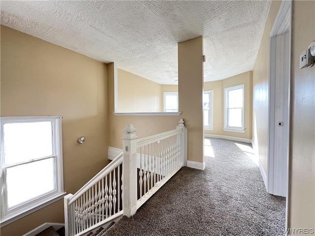 corridor with dark colored carpet and a textured ceiling