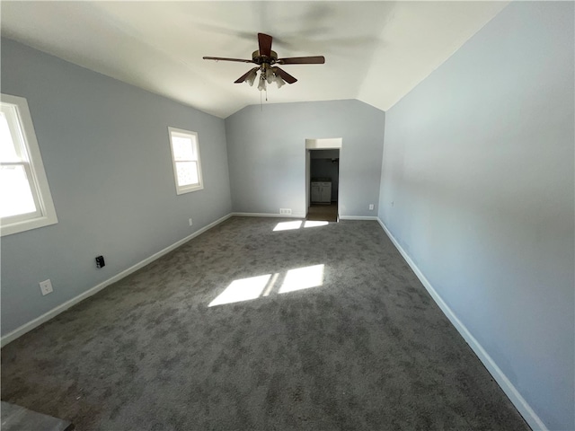 spare room featuring vaulted ceiling, ceiling fan, and dark colored carpet