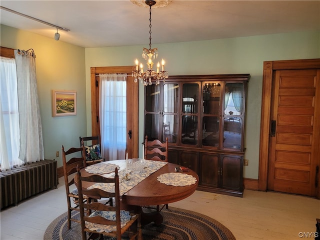 dining space featuring rail lighting, a chandelier, radiator, and light wood-type flooring