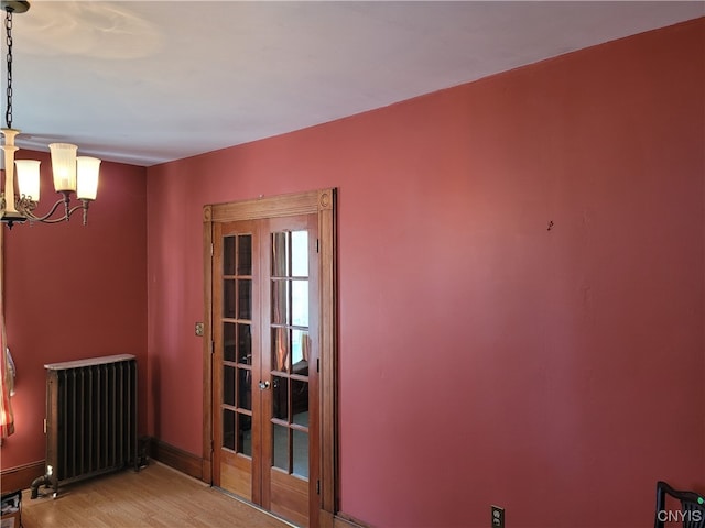 interior space with french doors, radiator, a chandelier, and light hardwood / wood-style flooring