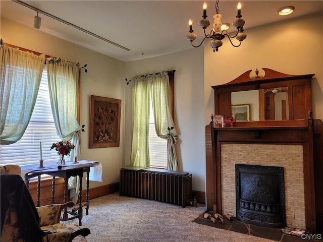 interior space featuring track lighting, a brick fireplace, radiator, and an inviting chandelier