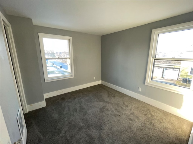 empty room featuring a healthy amount of sunlight and dark colored carpet