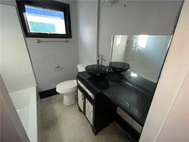 bathroom with concrete floors, vanity, a bath, and toilet