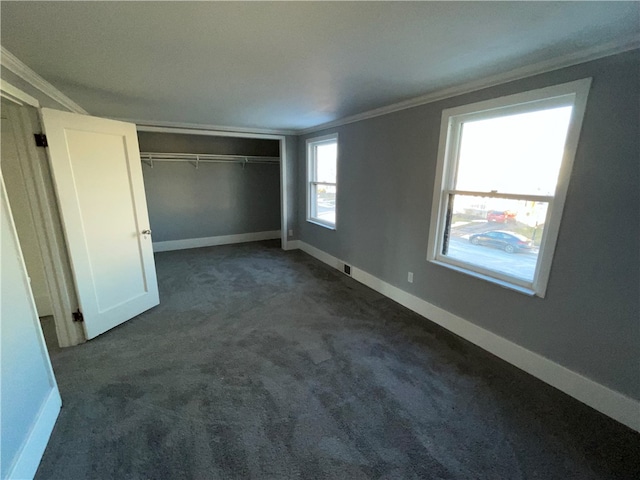 unfurnished bedroom featuring crown molding, a closet, and dark carpet