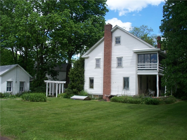 rear view of house featuring a balcony and a lawn