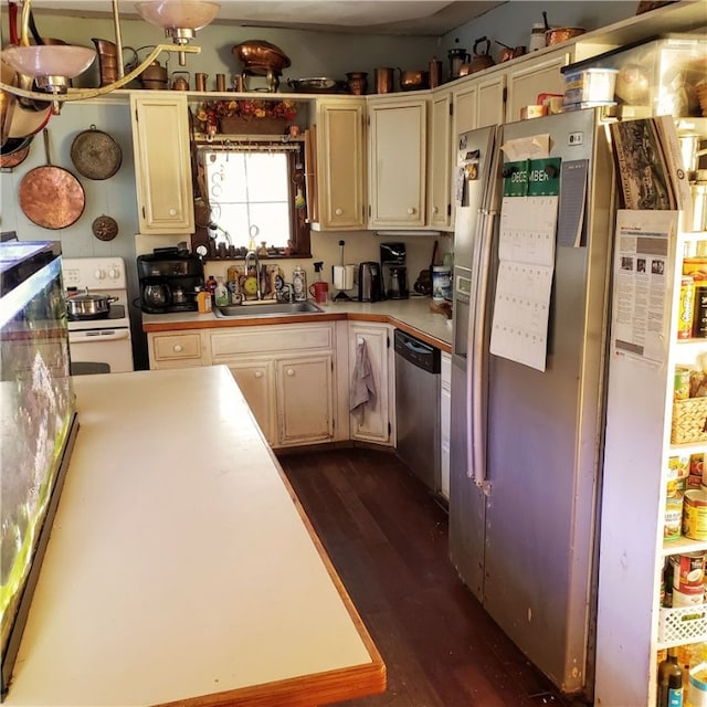 kitchen featuring cream cabinetry, dark wood-type flooring, appliances with stainless steel finishes, and sink