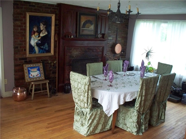 dining area featuring an inviting chandelier, light hardwood / wood-style floors, and a brick fireplace