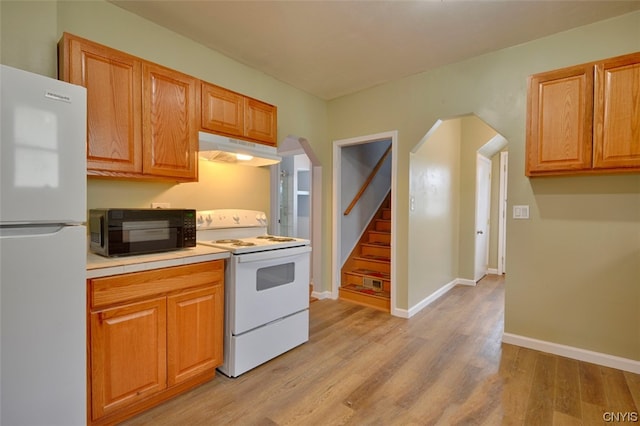 kitchen with white appliances and light hardwood / wood-style flooring