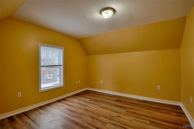 additional living space with vaulted ceiling and wood-type flooring