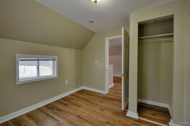 unfurnished bedroom with lofted ceiling, a closet, and light wood-type flooring