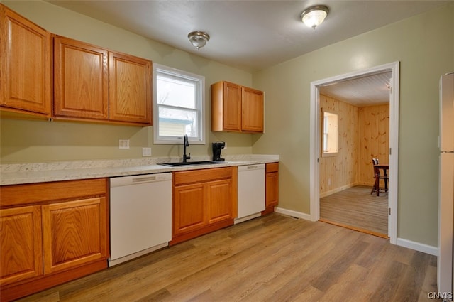 kitchen with wooden walls, sink, light hardwood / wood-style flooring, and white appliances