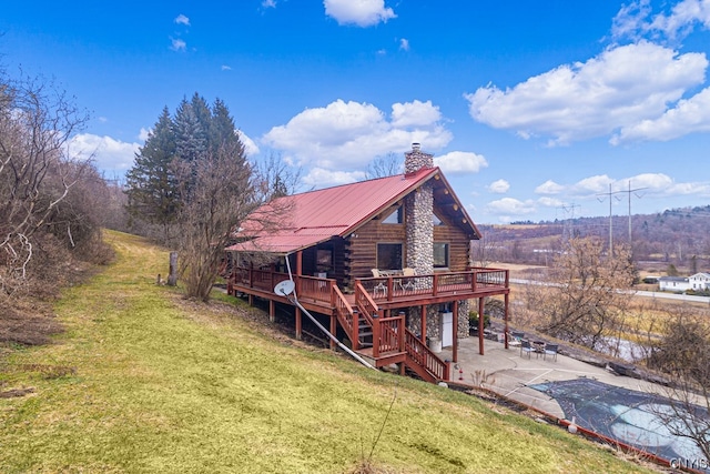 rear view of house featuring a lawn, a swimming pool side deck, a rural view, and a patio