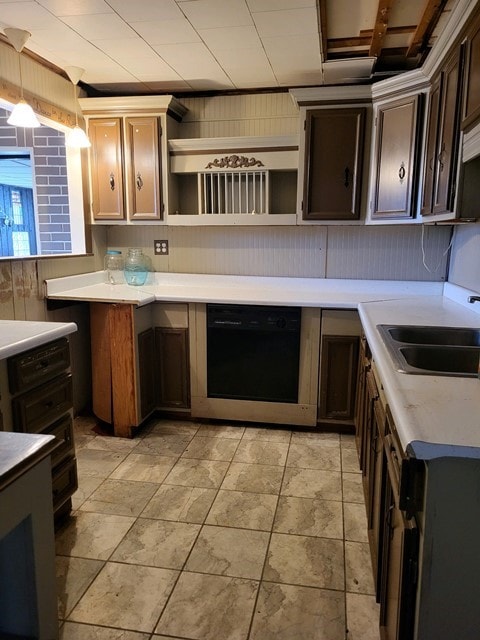 kitchen with sink, light tile floors, black dishwasher, decorative light fixtures, and dark brown cabinetry