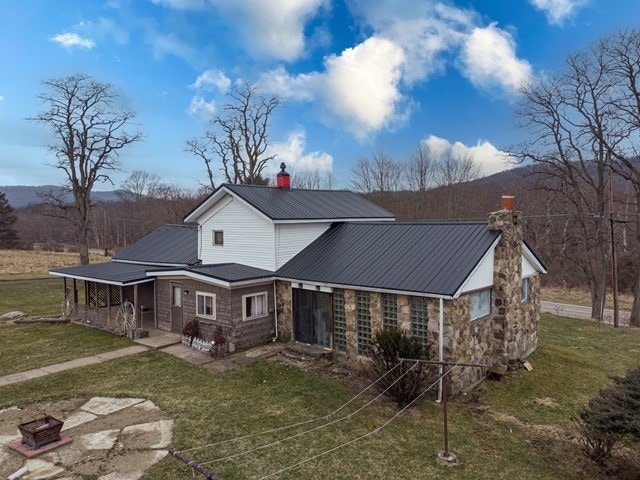 back of property featuring a lawn and an outdoor fire pit