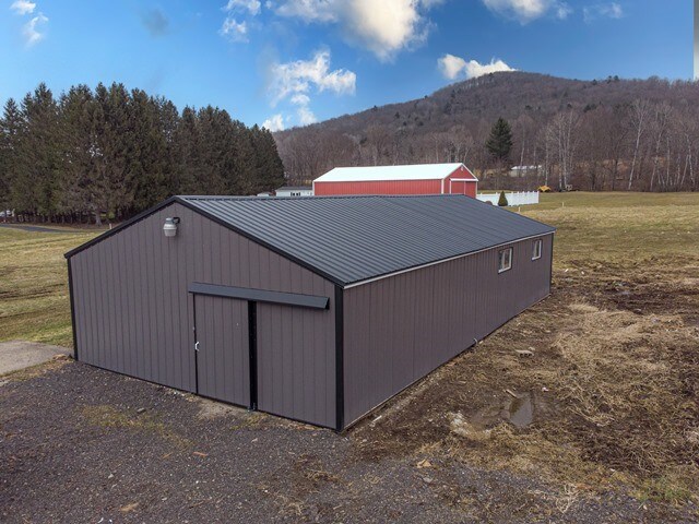 view of outdoor structure featuring a lawn, a mountain view, and a garage