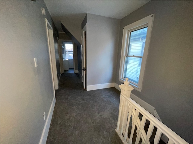 corridor with dark carpet and a wealth of natural light