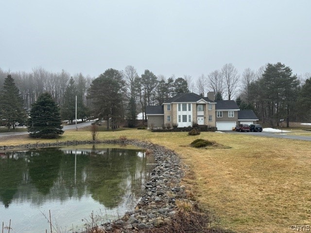 view of front facade with a water view and a front lawn