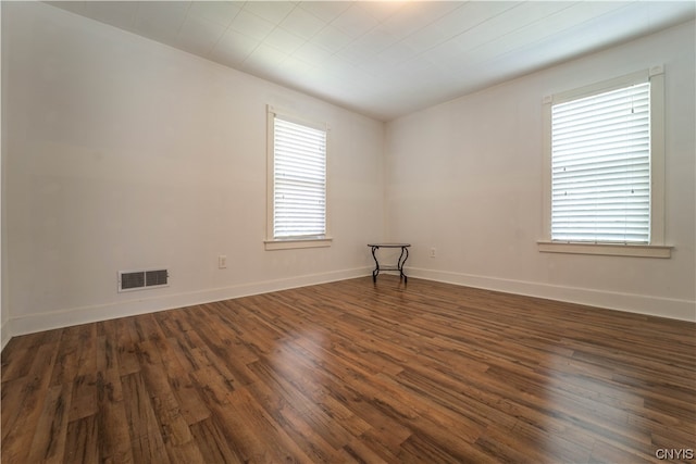 spare room featuring dark wood-type flooring and a healthy amount of sunlight