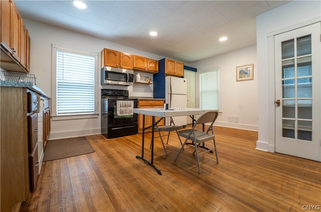 kitchen with light hardwood / wood-style flooring, white refrigerator, and black range with electric cooktop