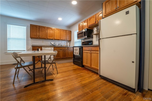 kitchen featuring tasteful backsplash, white appliances, and light wood-type flooring