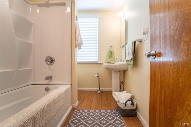 bathroom with plenty of natural light, hardwood / wood-style flooring, and washtub / shower combination