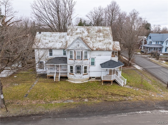 back of property with a yard and covered porch