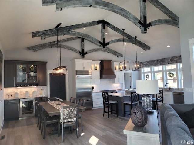 dining space featuring wine cooler, lofted ceiling, sink, and hardwood / wood-style floors