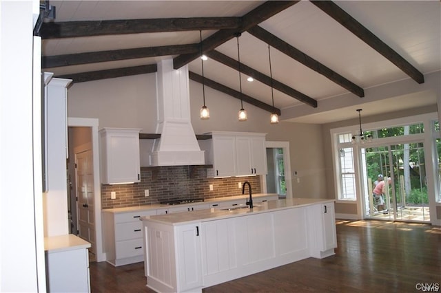 kitchen with hanging light fixtures, white cabinets, a kitchen island with sink, and lofted ceiling with beams