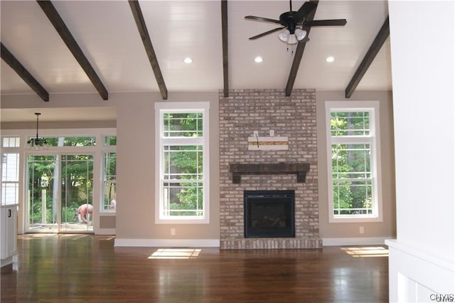 unfurnished living room featuring a brick fireplace, a wealth of natural light, and beamed ceiling