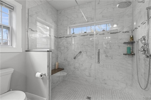 bathroom with a shower with shower door and toilet